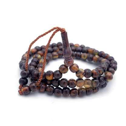 Brown and black patterned wooden Islamic misbaha prayer beads with braided tassel cord.